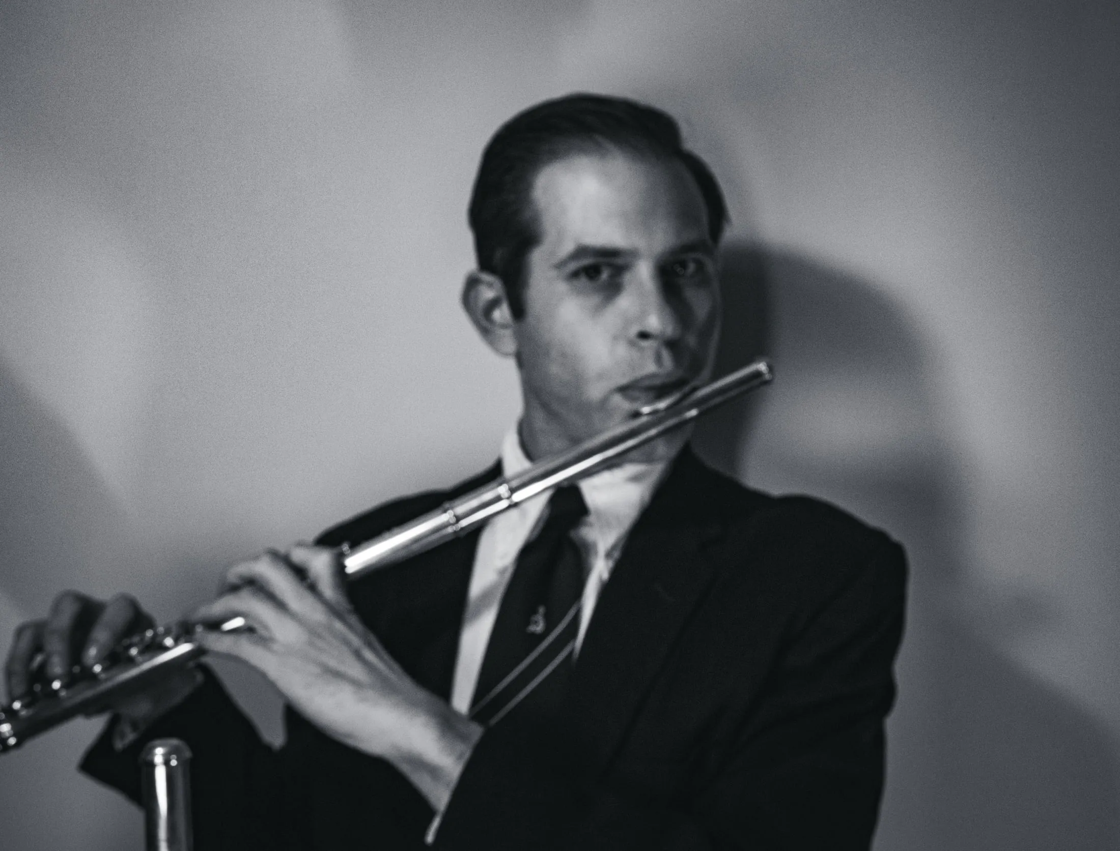High-key black and white portrait of Aaron Johnson playing the concert flute.