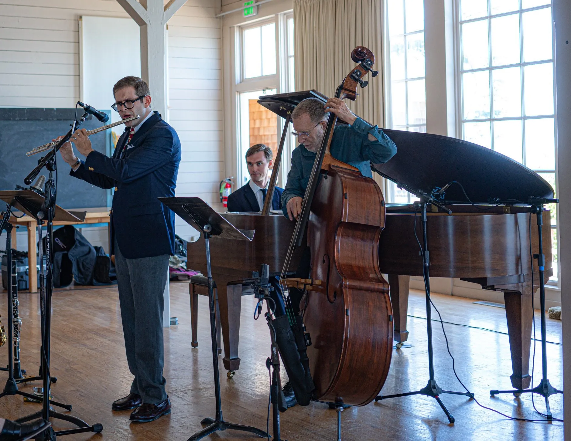Aaron Johnson playing alongside a bassist and pianist in a bright, white-walled hall.